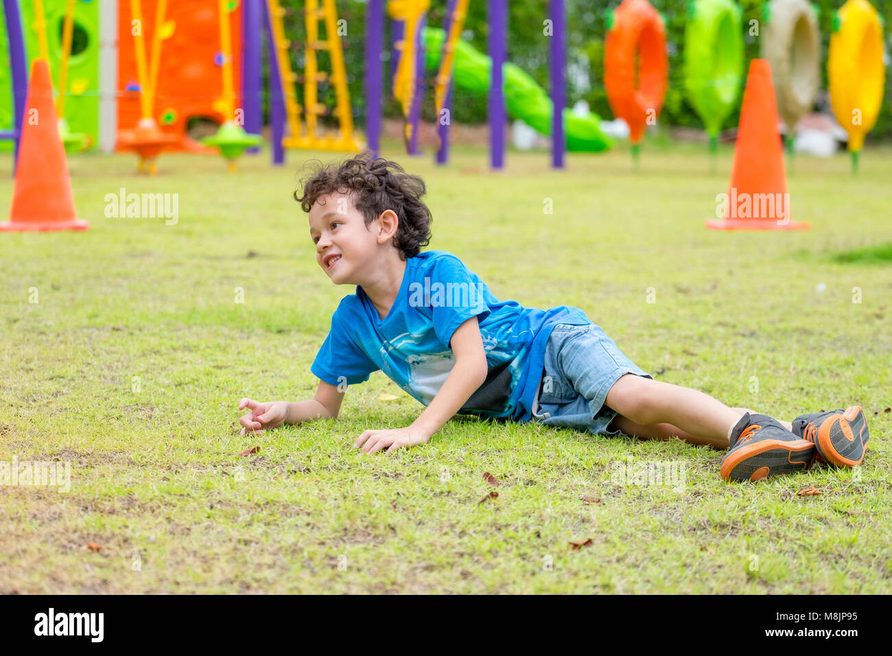 kid boy having fun to play children's playground area at school,kid running and fall down on grass.back to school outdoor activity Stock Photo