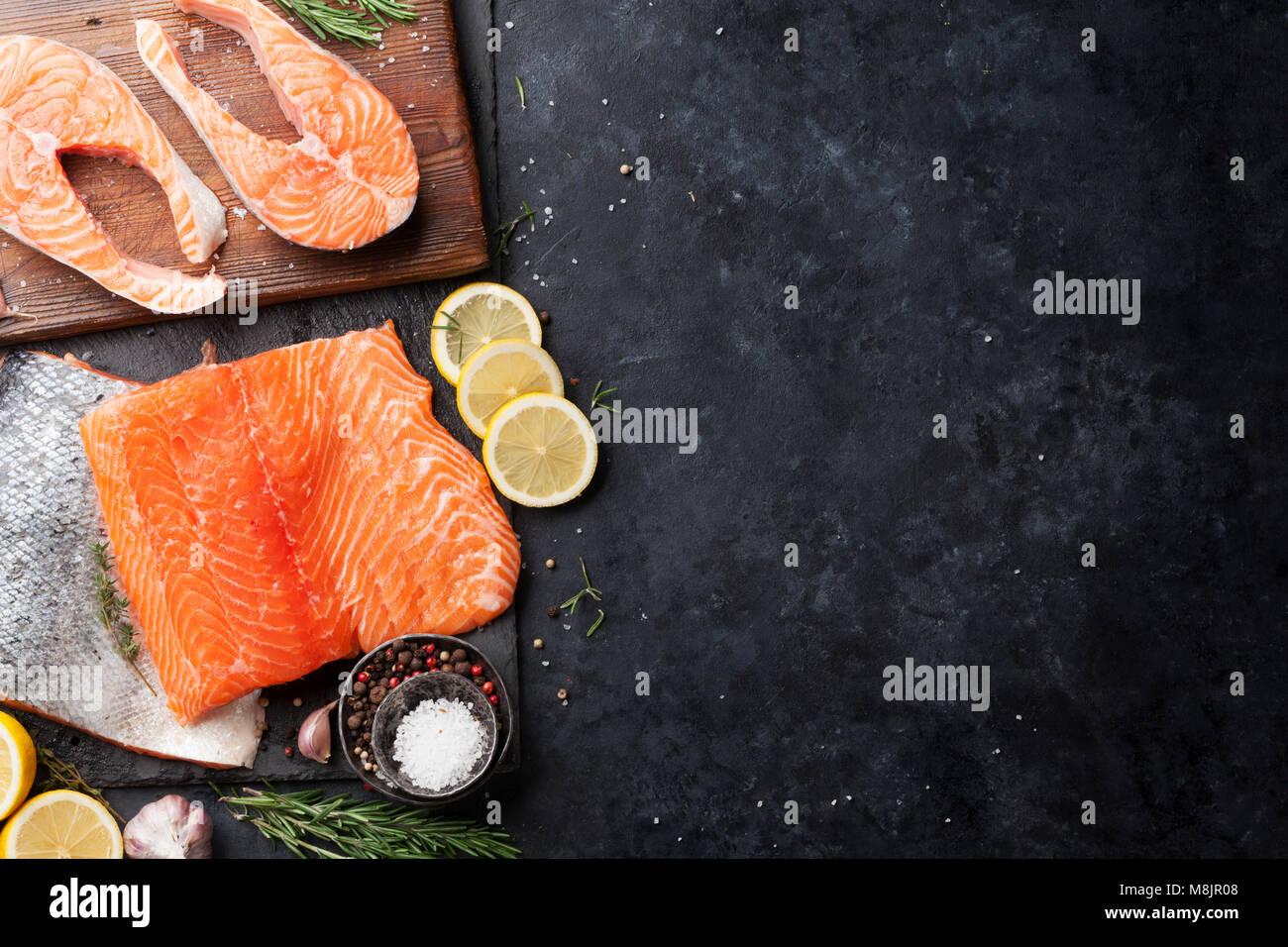 Raw salmon fish steaks with spices cooking on cutting board. Top view ...
