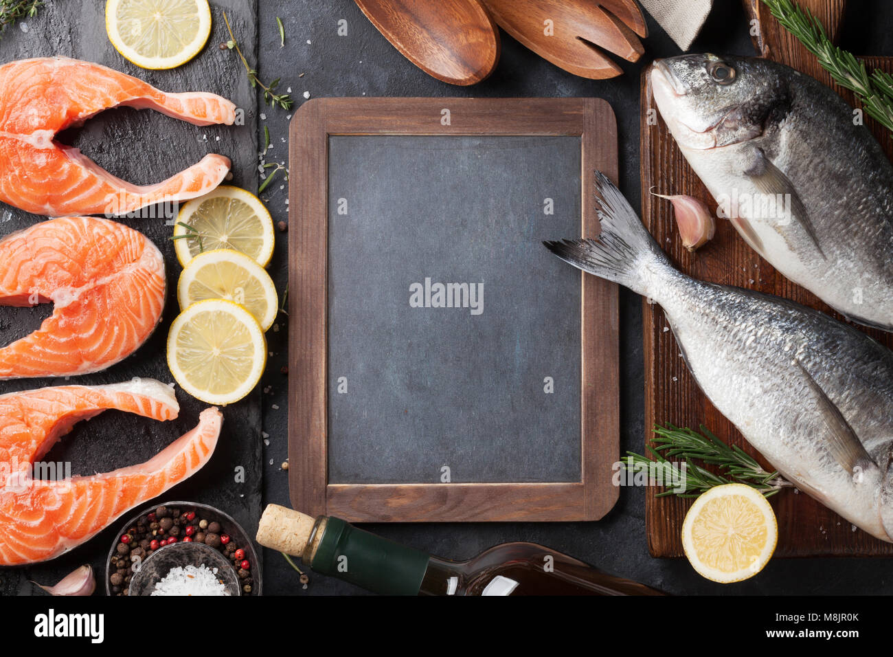Raw salmon fish fillet and dorado with spices cooking on cutting board ...
