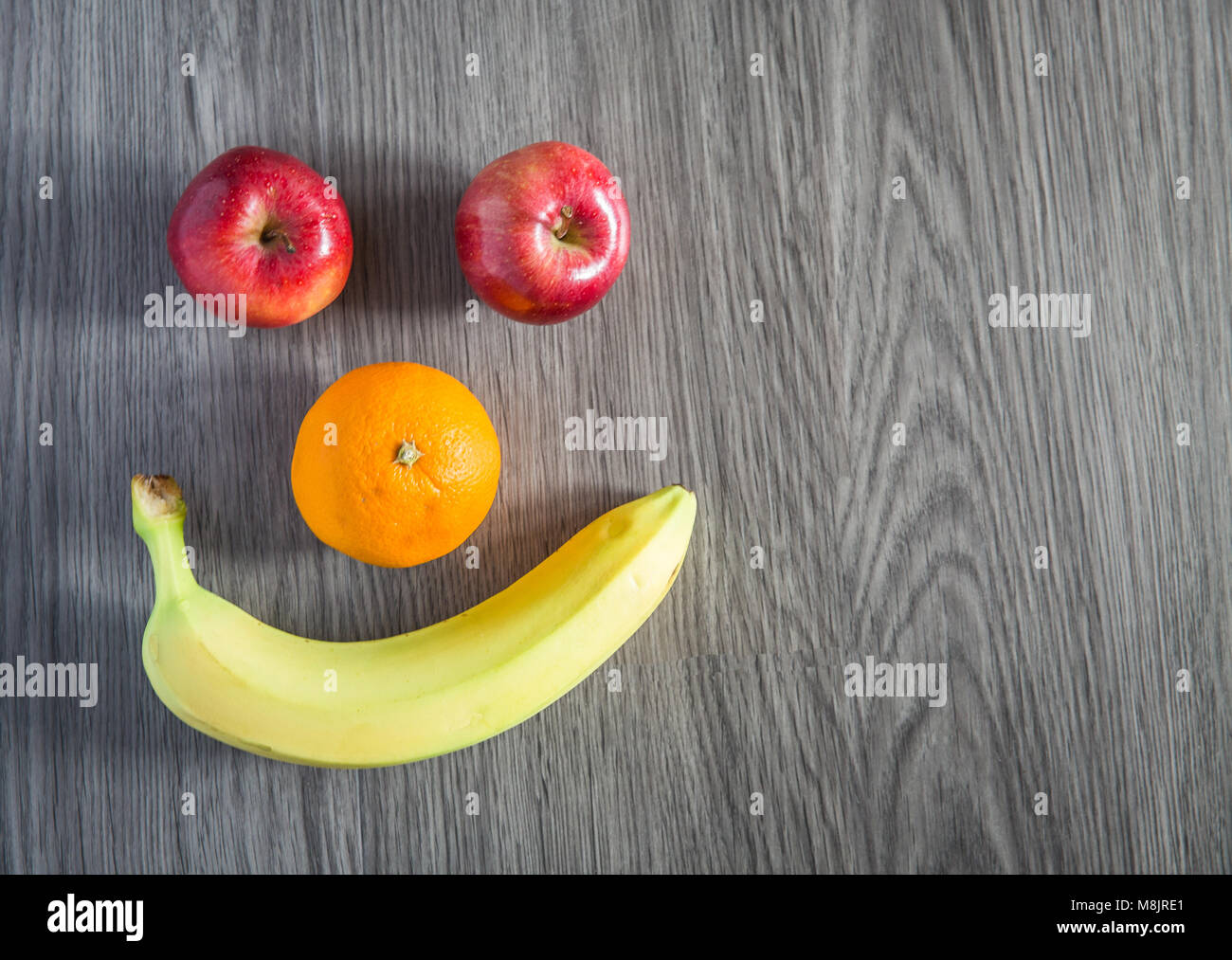 Different kinds of fruit including apples, oranges and bananas arranged into a smiling face to encourage children to eat healthily. Stock Photo