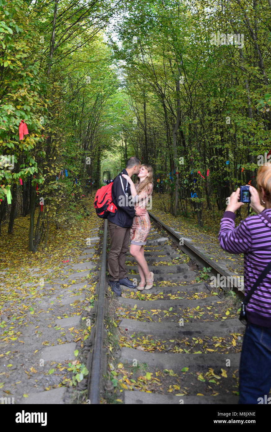 A young couple, kissing each other at the tunnel of Love, near Rivne, Ukraine Stock Photo