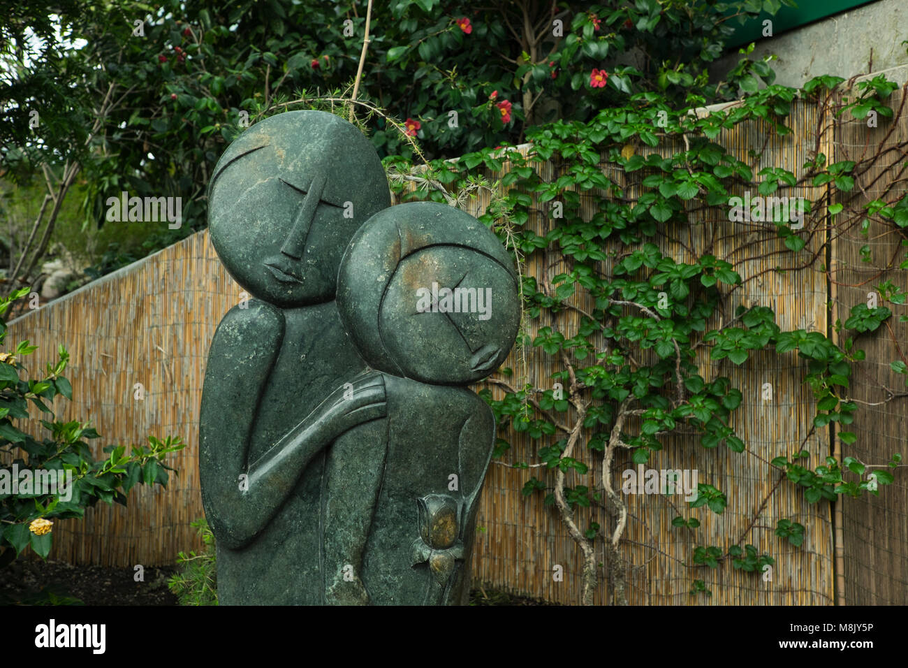 Garden sculpture of man and woman with ivy covered wall, Muttart
