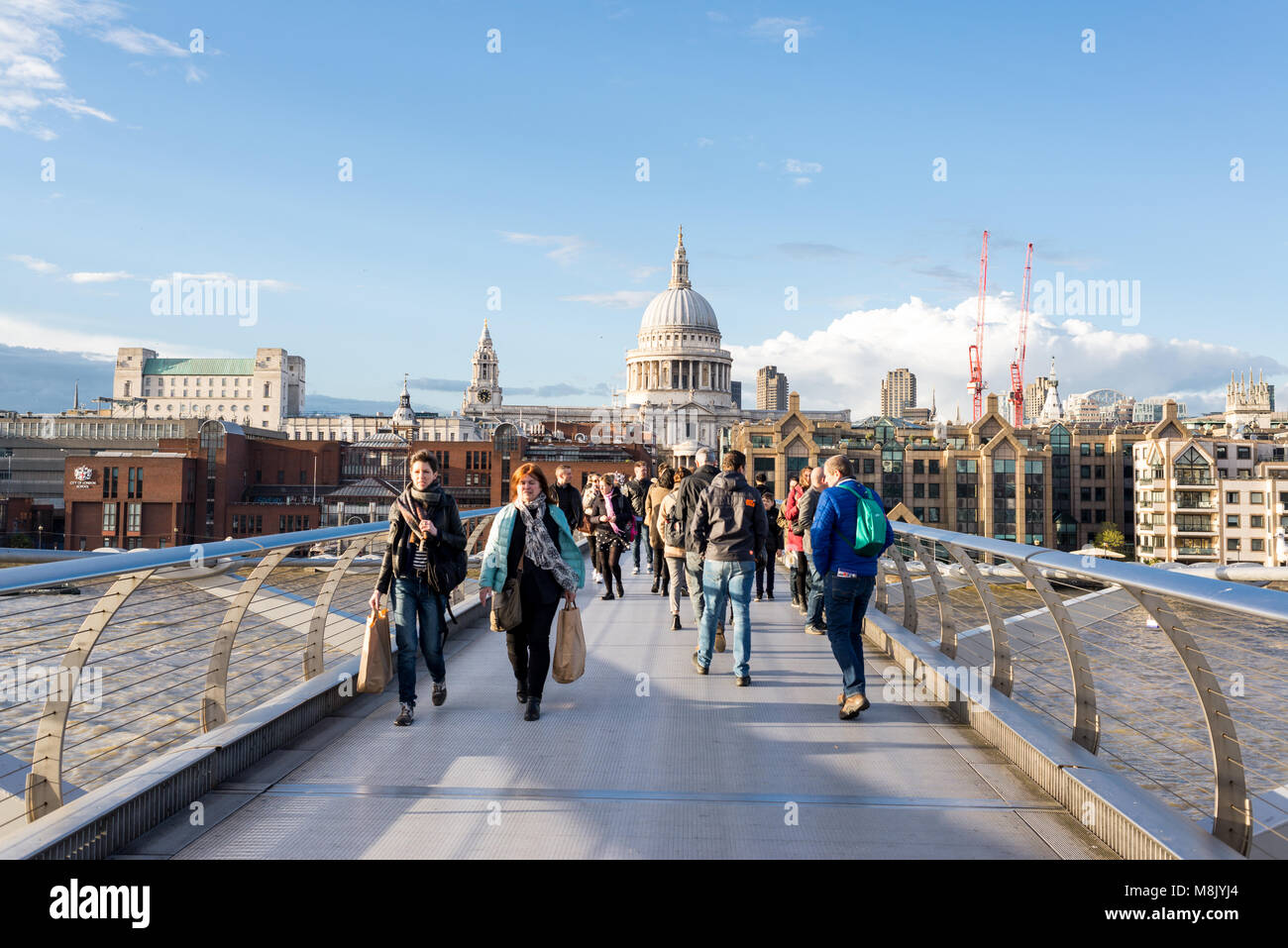 London, UK - April 2017: People walking on the Millenium bridge crossing the river Thames with view of St Paul's Cathedral on a sunny day Stock Photo