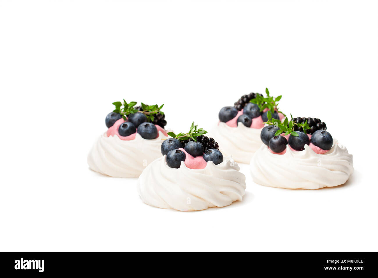 Mini  Pavlova meringue nests with berries and thyme isolated on white Stock Photo