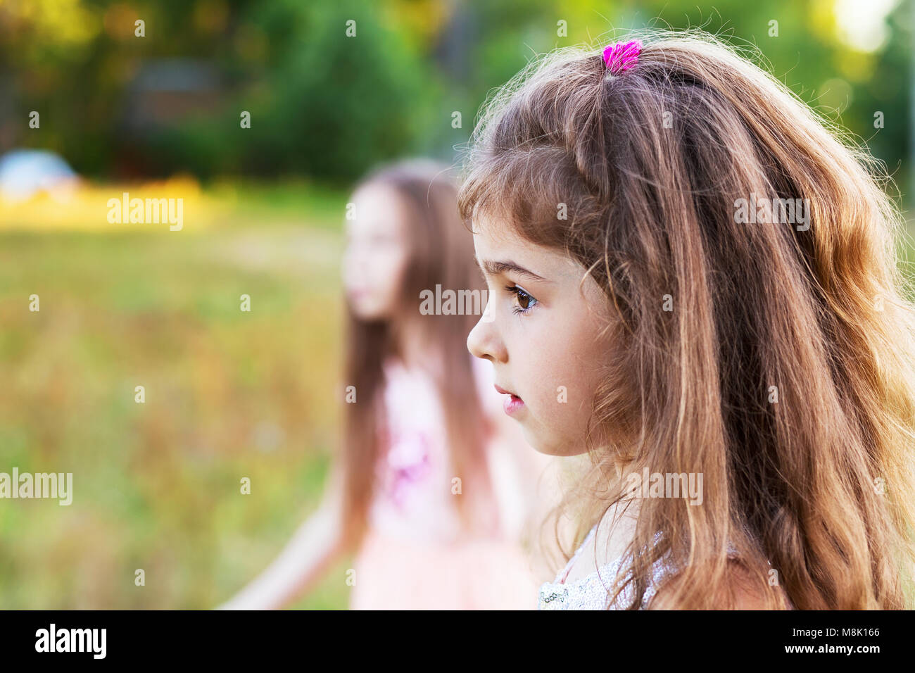 Beautiful little girl with long curly hair, looking worried at summer day.  Place for text Stock Photo