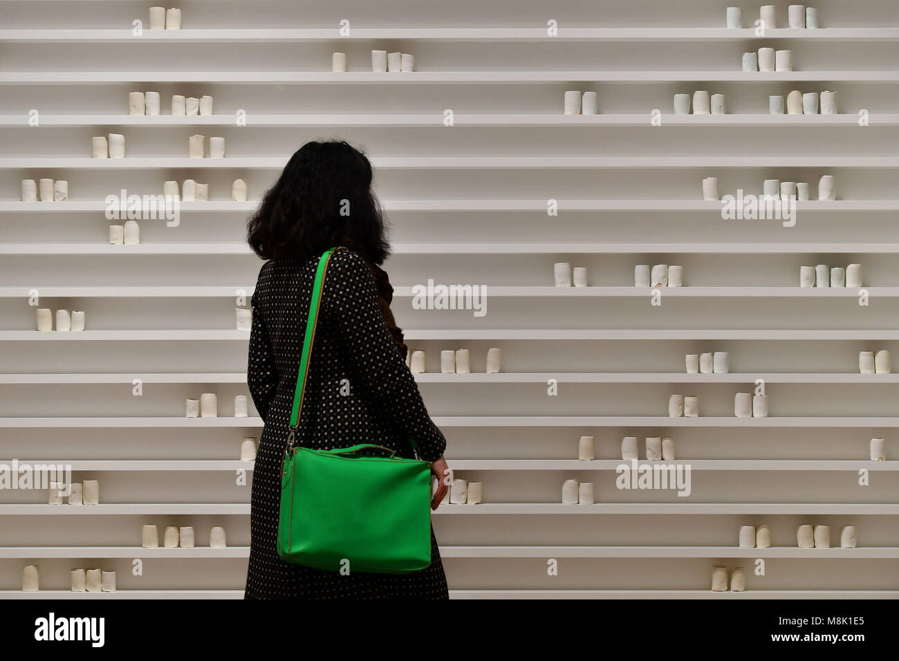 A visitor views a place made fast, a piece by Edmund de Waal, in the Things of Beauty Growing exhibition at the Fitzwilliam Museum in Cambridge, where over 100 pieces are on show in the largest and first exhibition to explore the evolution of British ceramics over half a century of creativity. Stock Photo