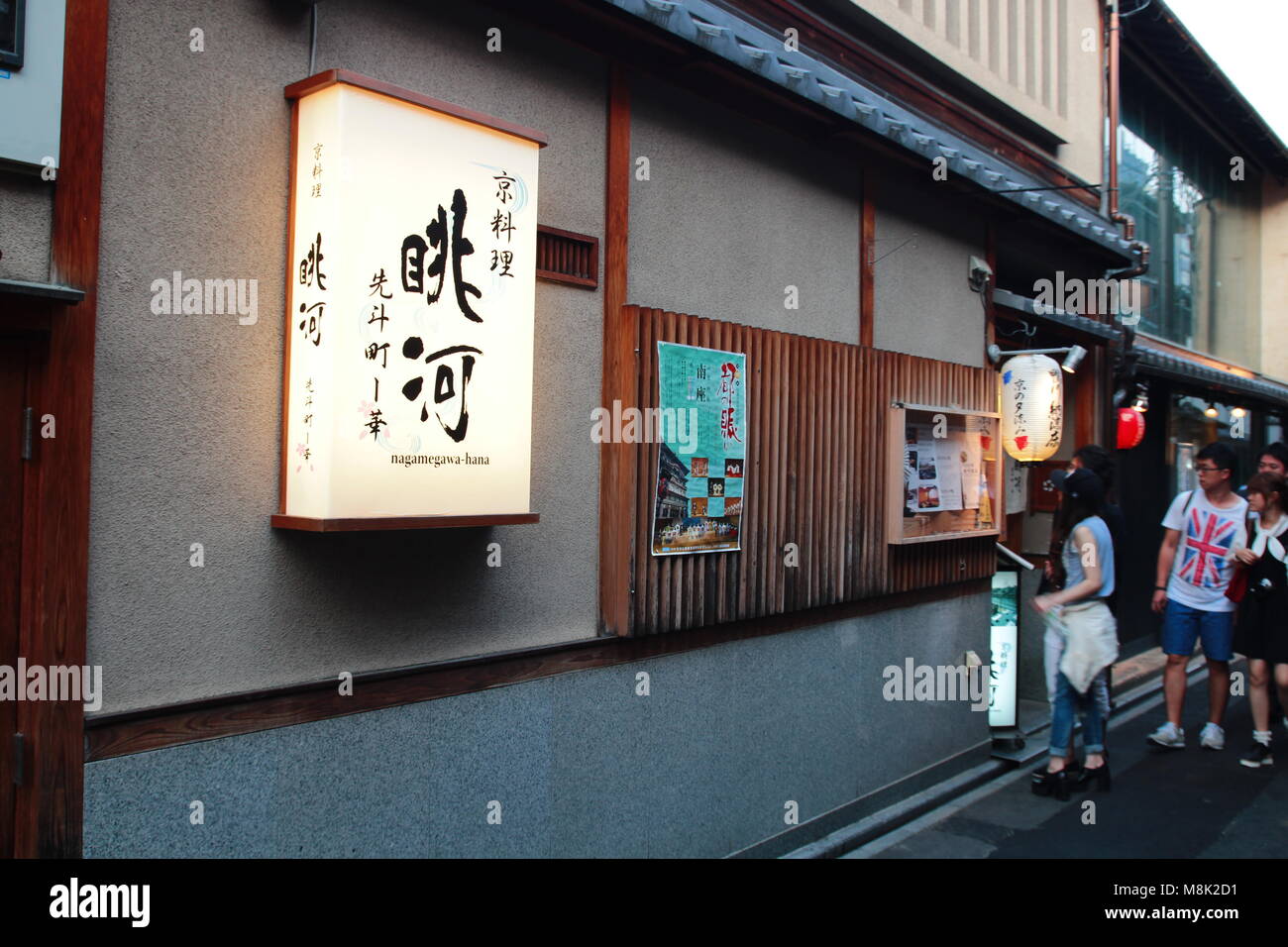 Japanese izakaya restaurant located at the narrow street in the Pontocho Alley of downtown Kyoto, Japan at dusk. Customers looking at the menu. Stock Photo