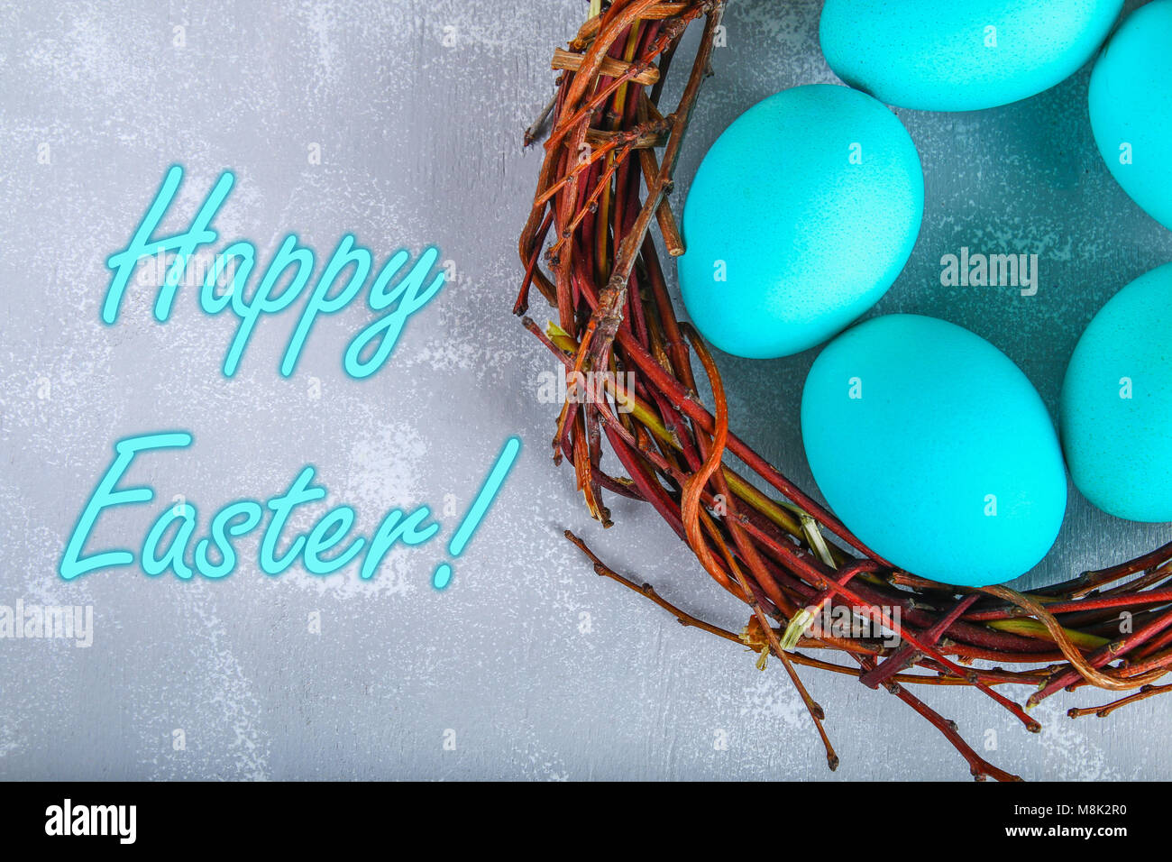 Blue easter eggs in a nest with white flowers on a gray concrete ...