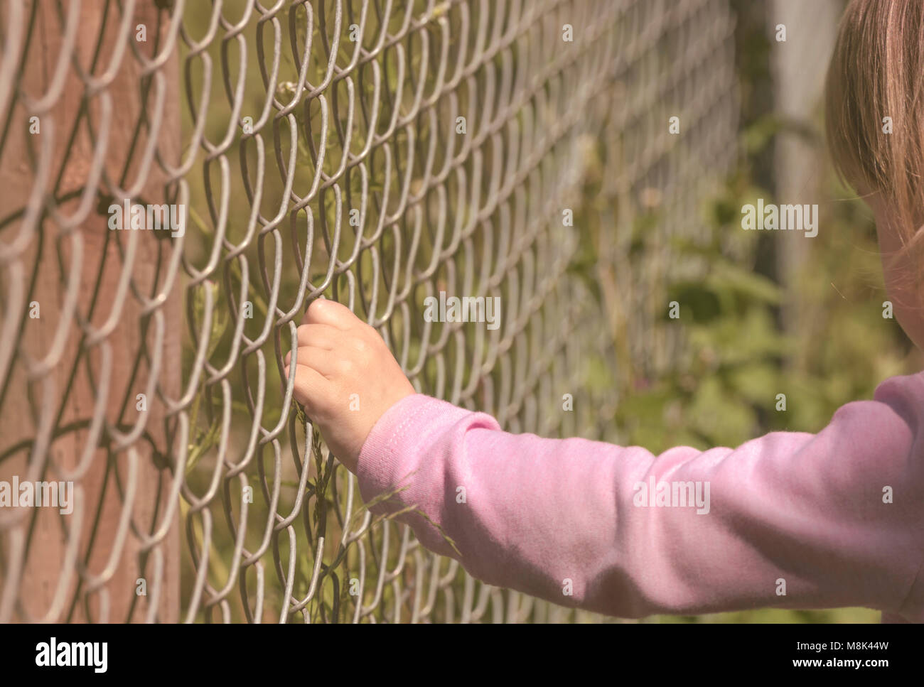 Close up image of blonde little's girl hand grabbing the metal fence Stock Photo