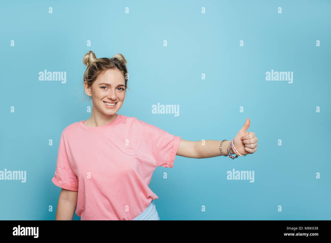 modern young woman on a blue background, thumbs up Stock Photo