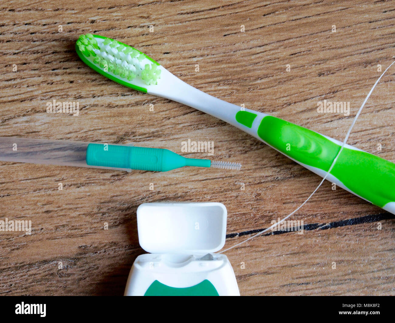 Dental floss, interdental brush and toothbrush on wood background Stock