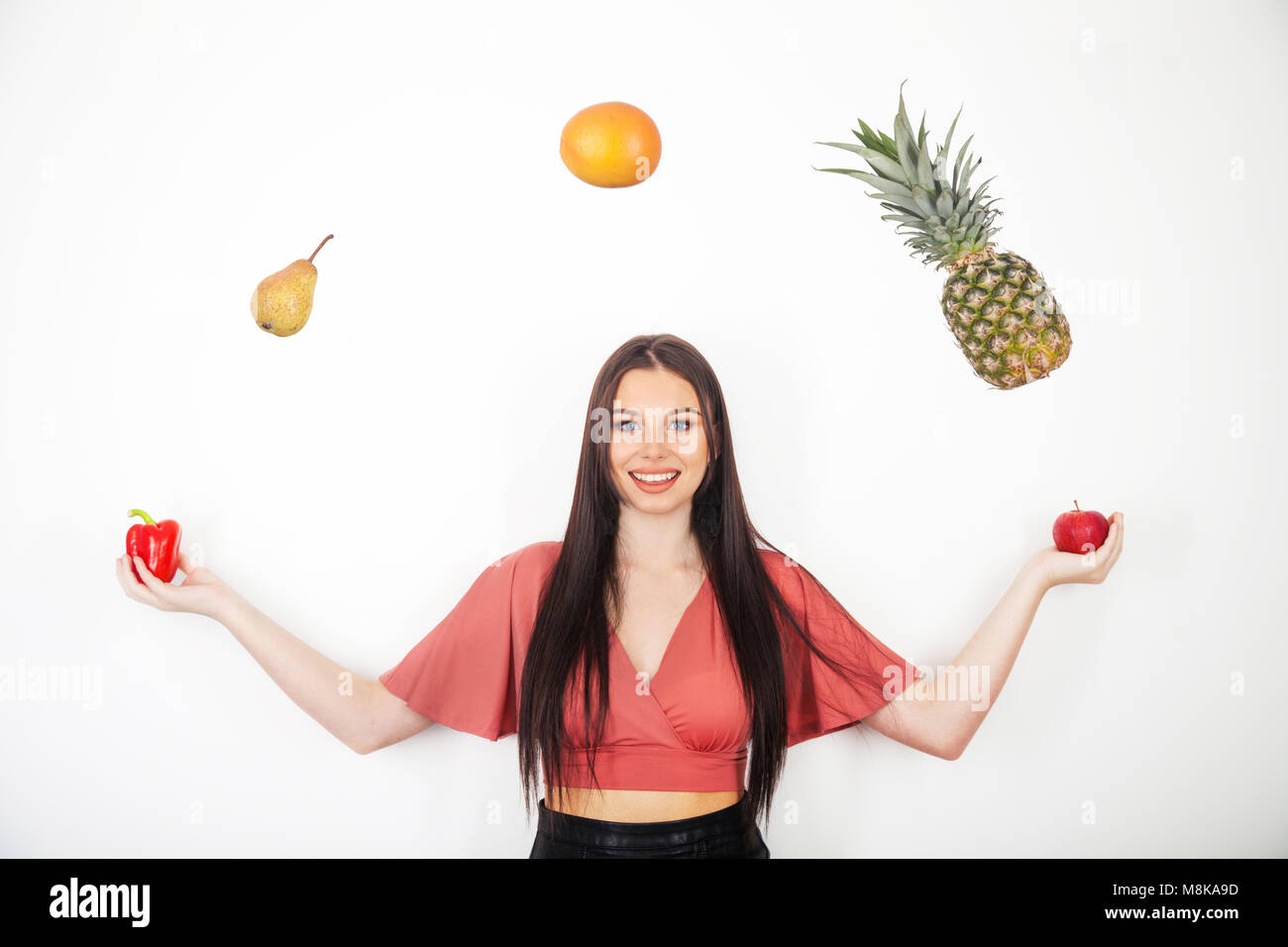 A pretty teenage girl juggling her five a day of fruit and veg Stock Photo