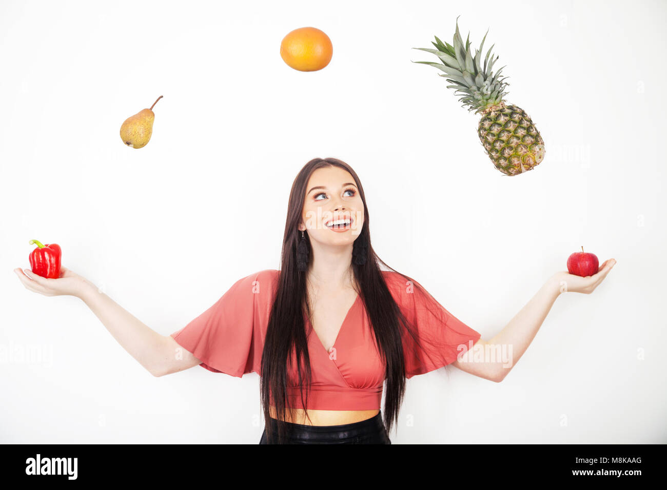 A pretty teenage girl juggling her five a day of fruit and veg Stock Photo