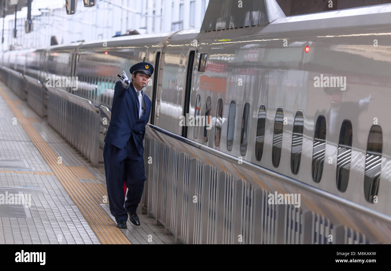 Bullet Train Shinkansen in Tokyo station with a conductor signaling the imminent departure to the train driver. Stock Photo