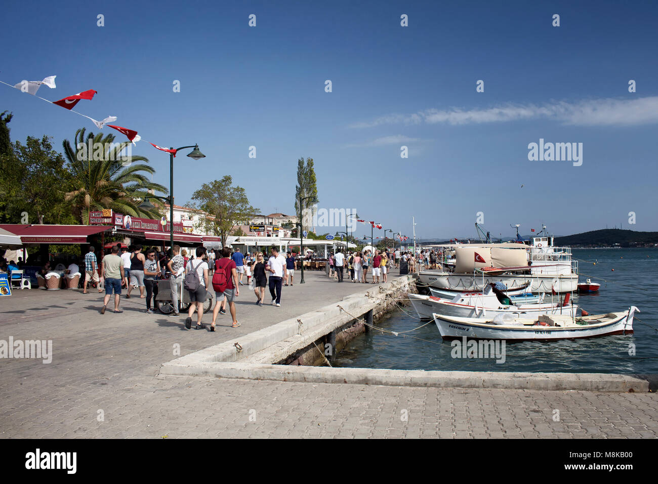 Many people walk by Aegean sea in old town of Cunda (Alibey) Island. Sunny summer day. Stock Photo