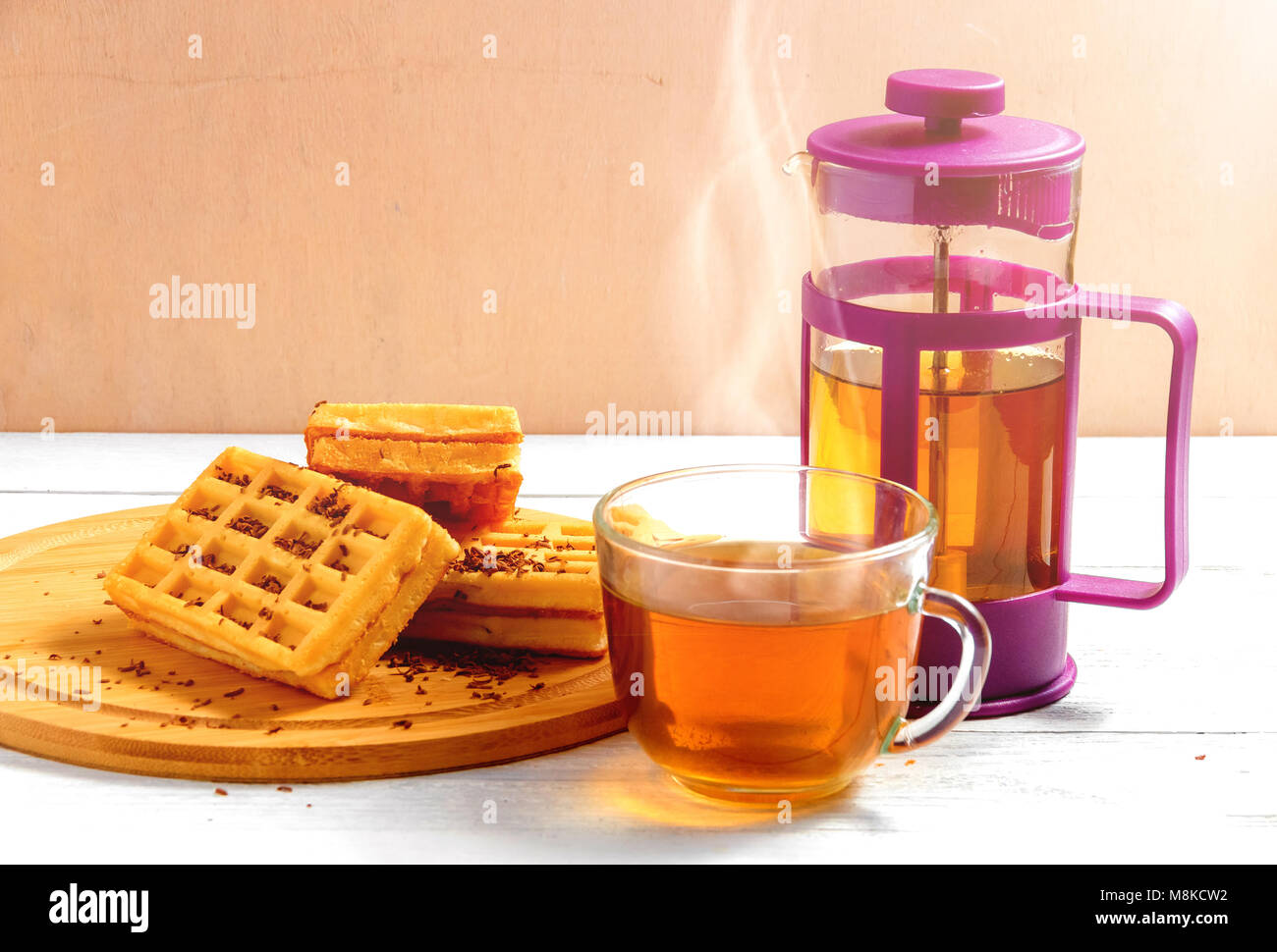 Homemade waffles with jam on old wooden table. Wafers with cup of tea with teapot. Stock Photo