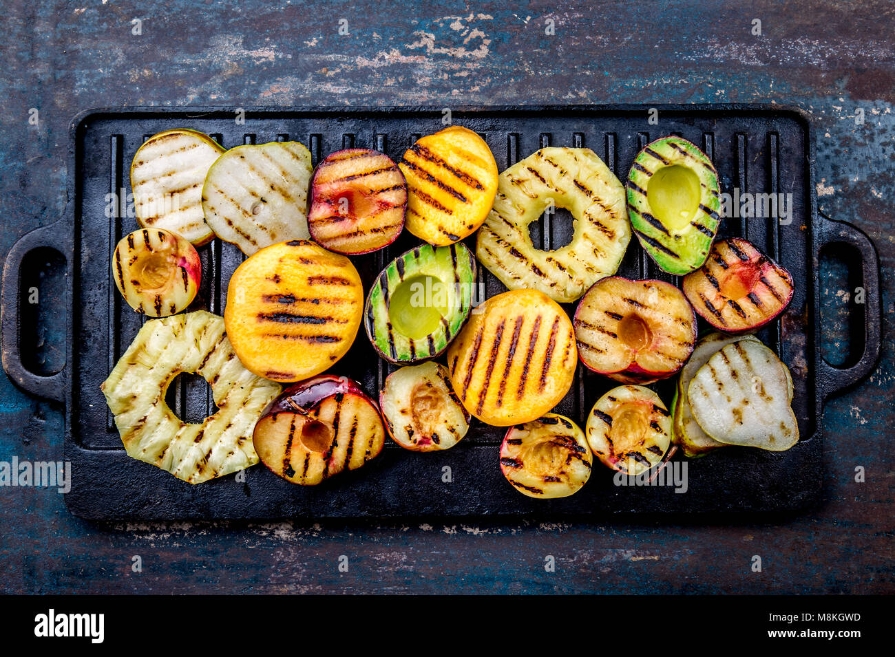 GRILLED FRUITS. Grill fruits pineapple, peaches, plums, avocado, pear on black cast iron grill
