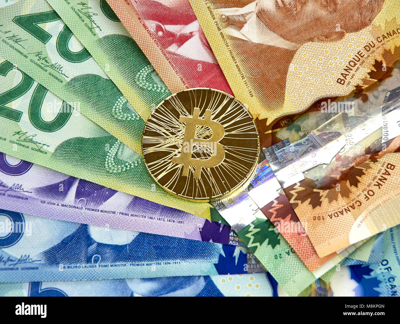 MONTREAL, CANADA - MARCH 10, 2018: Gold bitcoin cryptocurrency on canadian  bank notes Stock Photo - Alamy