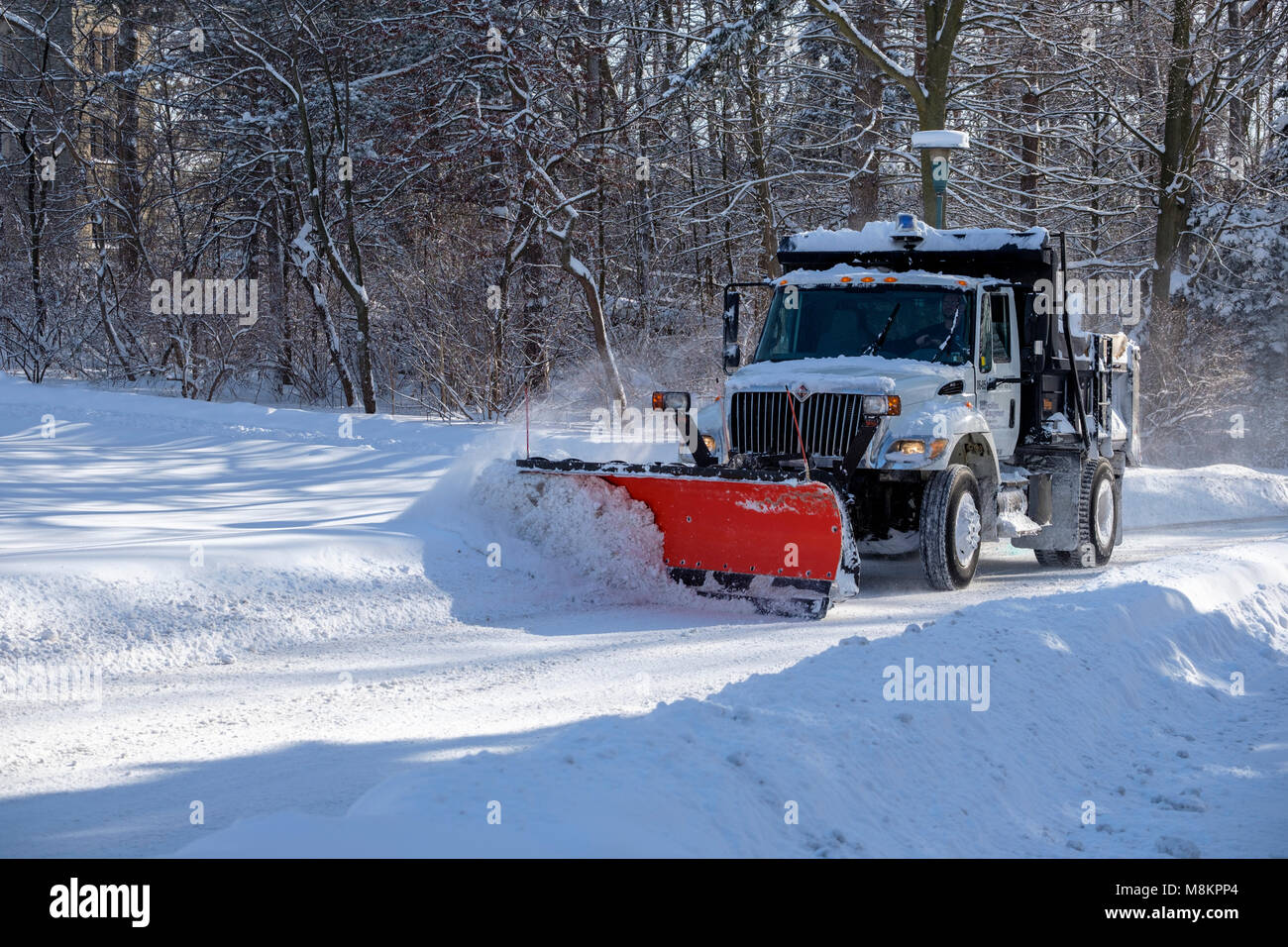 Snow plow truck in motion clearing a municipal road, street, after heavy snowfall at Western University, London, Ontario, Canada. Stock Photo