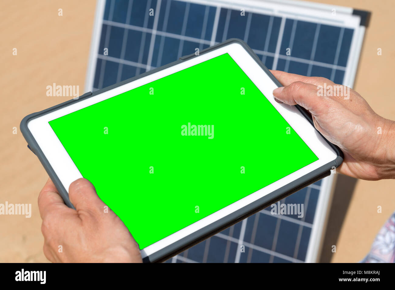 Woman hands on electronic tablet controlling her solar panel (green screen) Stock Photo