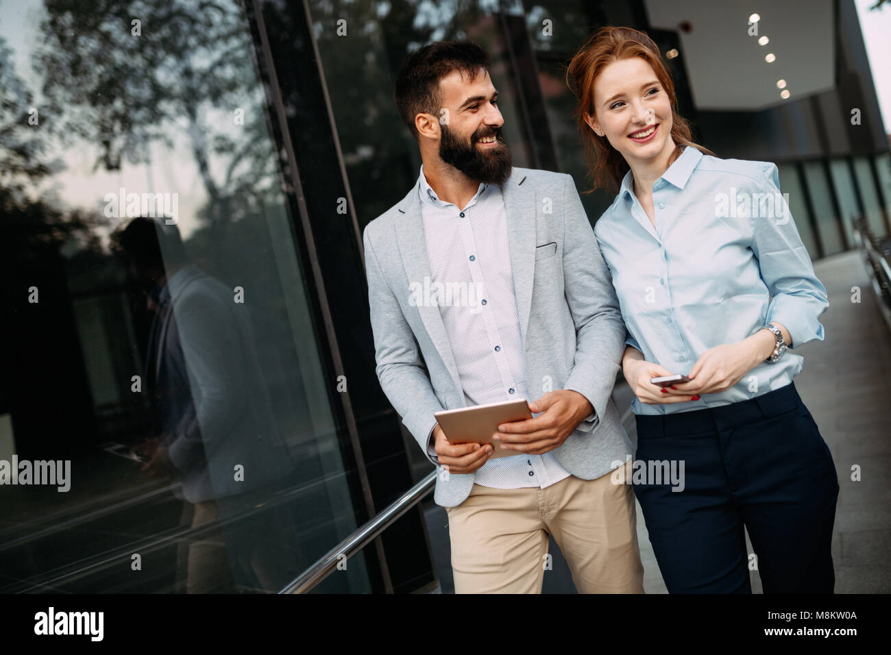 Young business couple walking outdoor near office building Stock Photo ...