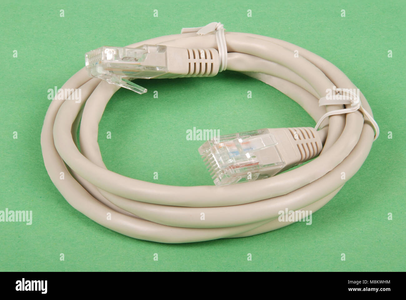 Patch cord grey network cable with molded RJ45 plug, isolated on a green background Stock Photo