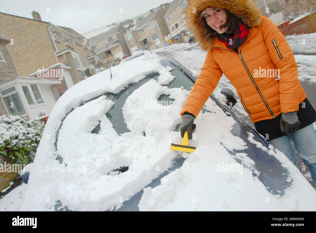 Portland, Dorset. 18th March 2018 - In the Dorset village of Fortuneswell, Isle of Portland, Sophie, 22,  enjoys making a cartoon face in the thick snow on the family car Credit: stuart fretwell/Alamy Live News Stock Photo