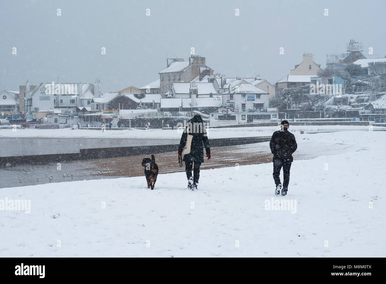 Weather Lyme Regis, UK 18 March 2018. A couple walk their dog on the