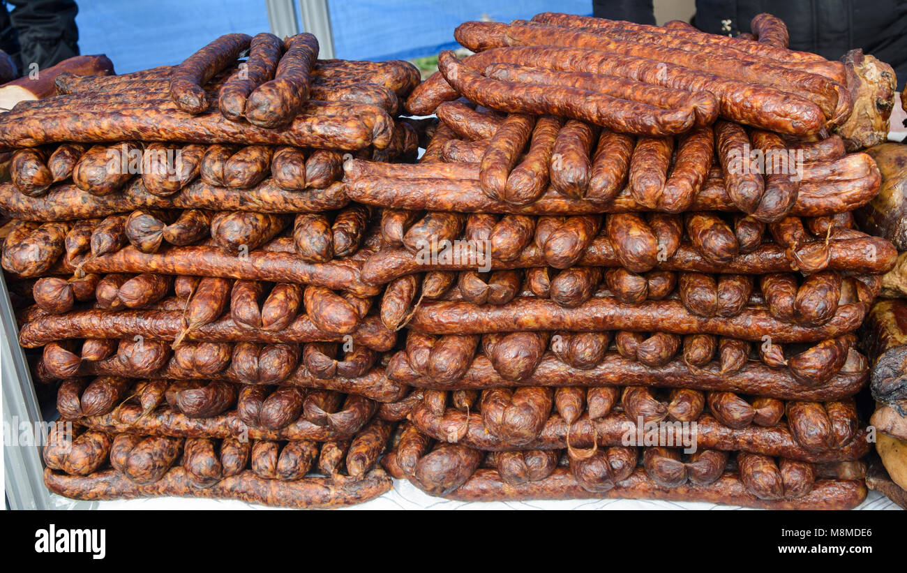Homemade sausages of pork smoked and dried stand on the table for sale