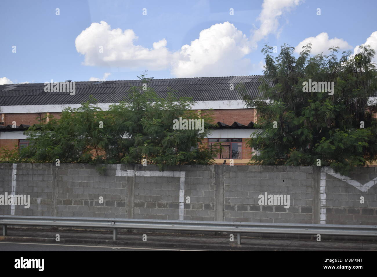 Industrial shed behind gray brick wall Stock Photo