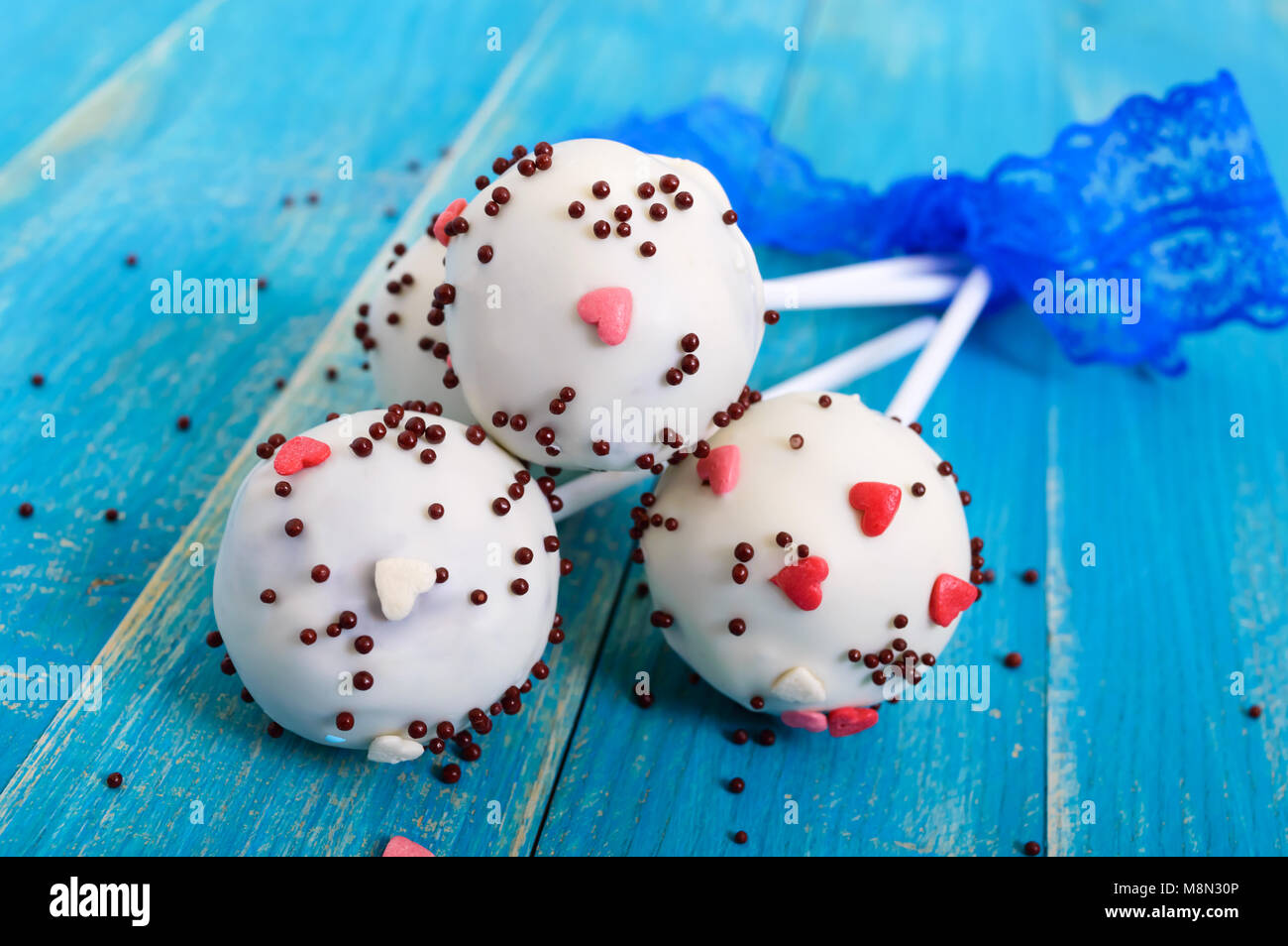 Holiday treats. Cake pops. Biscuit cakes in white chocolate glaze on a  bright blue wooden background Stock Photo - Alamy