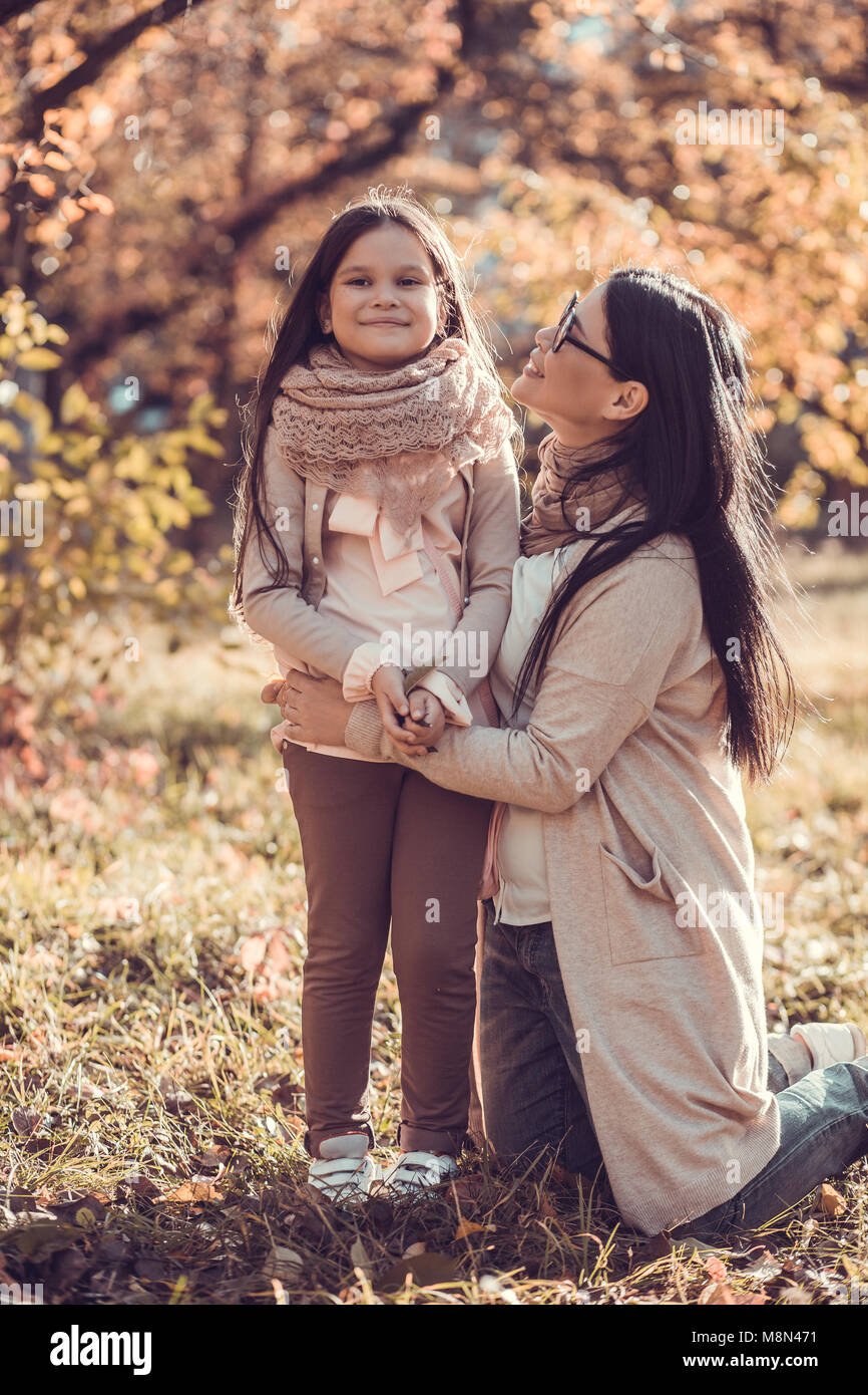 Beautiful young woman and her kid in autumn garden Stock Photo