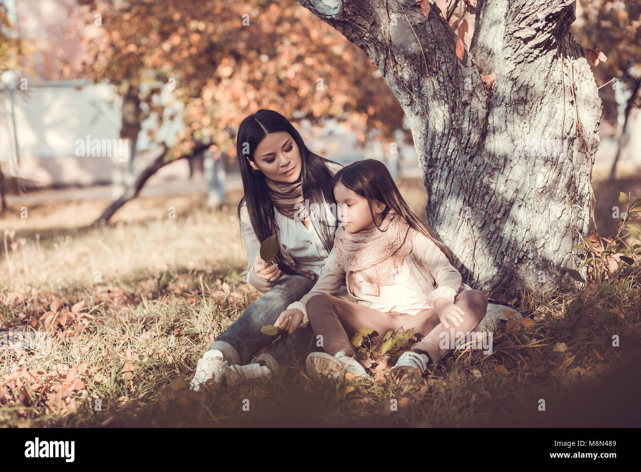 Beautiful young woman and her kid in autumn garden Stock Photo