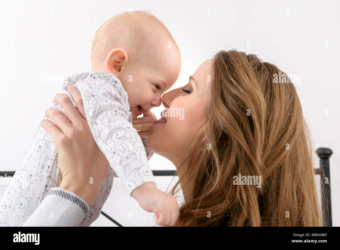 Happy mother and her baby son playing on a bed together. Happy family. Mother and newborn child portrait. Stock Photo