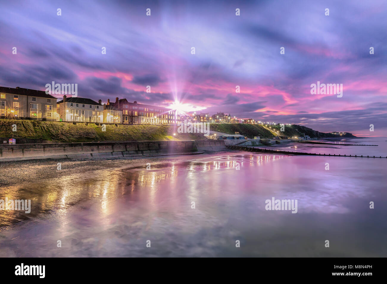 Sunburst over Cromer town - As dusk appears, the soft lights of streets and buildings come on. Cromer has one of the best, and flourishing, piers in E Stock Photo