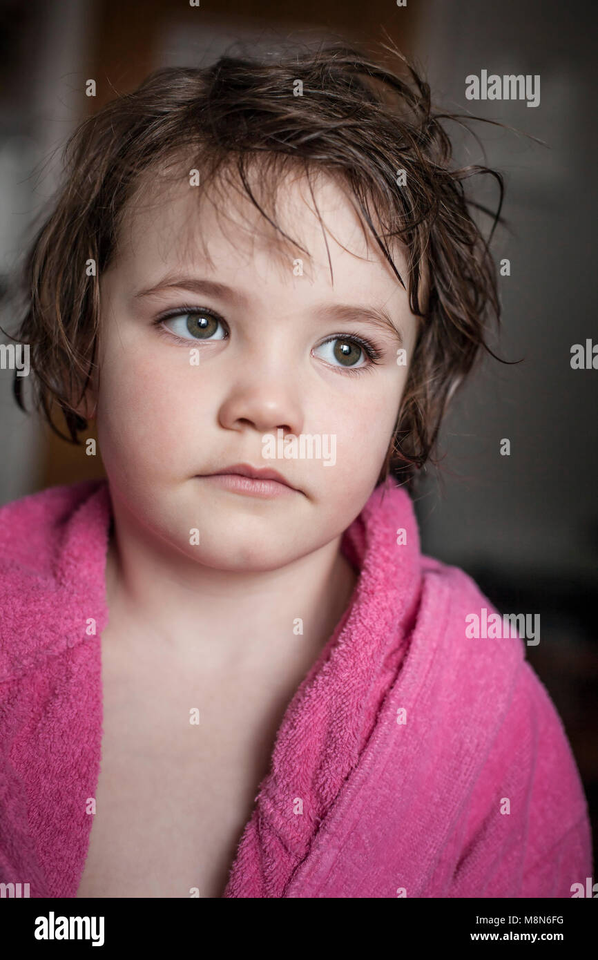 Sad young girl in bathrobe with short wet hair at home Stock Photo