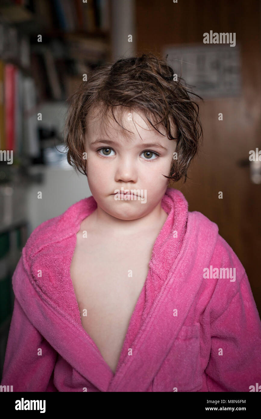 Sad young girl in bathrobe with short wet hair at home Stock Photo