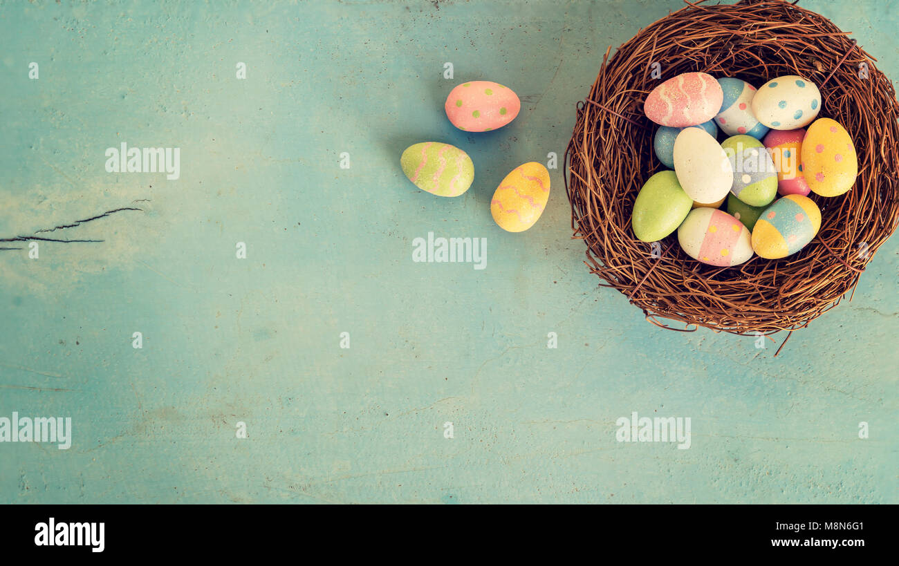 Colorful easter eggs in nest on wood pastel color background with space ...