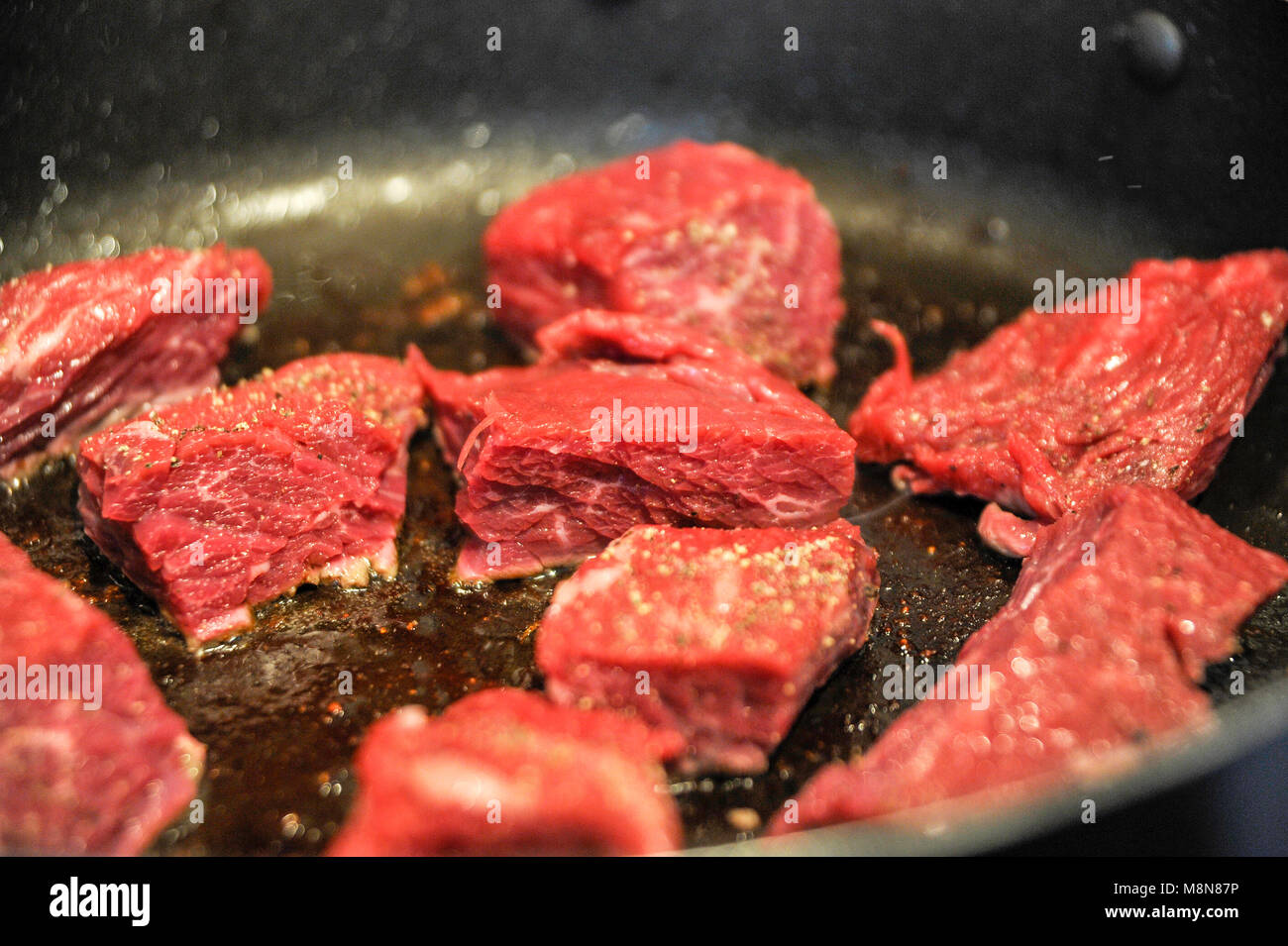 Browning off beef skirt steak and an ox tail meat in frying pan for a casserole Photograph taken by Simon Dack Stock Photo