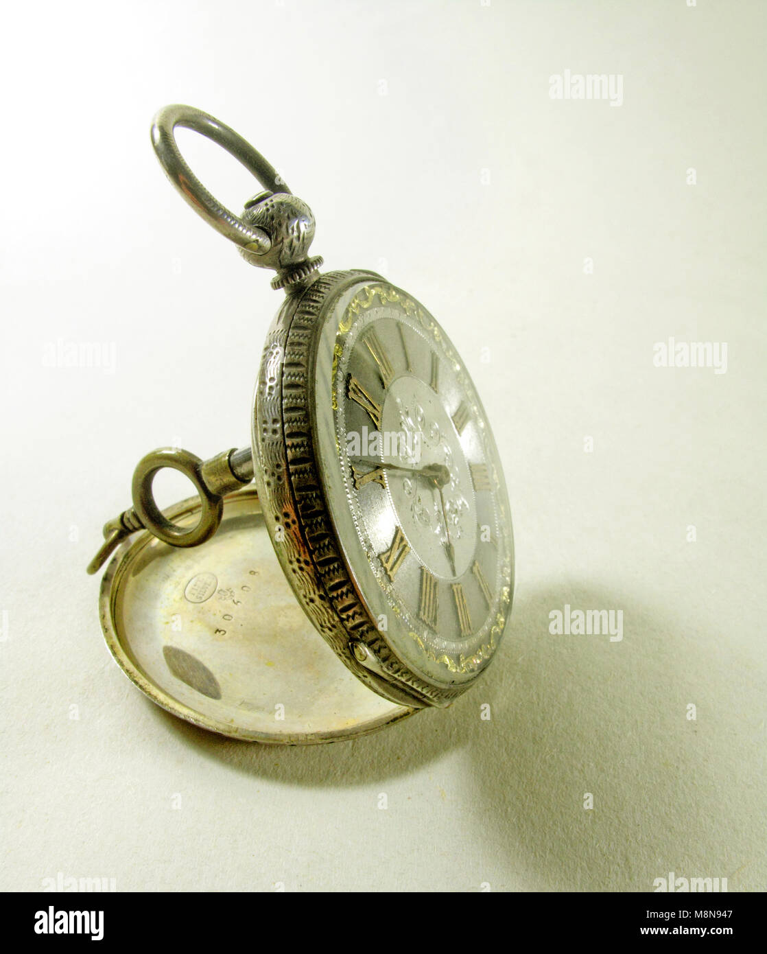 antique pocket watch with winding key seen from the side Stock Photo