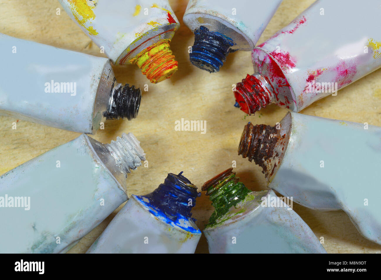 Close view of tubes of colorful paint in a circular form isolated on wooden background Stock Photo