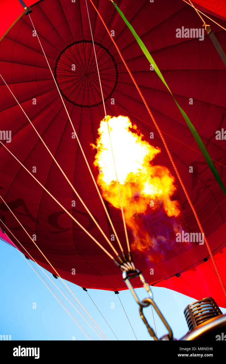 Gas firing hot air into a red hot air balloon, ready for takeoff
