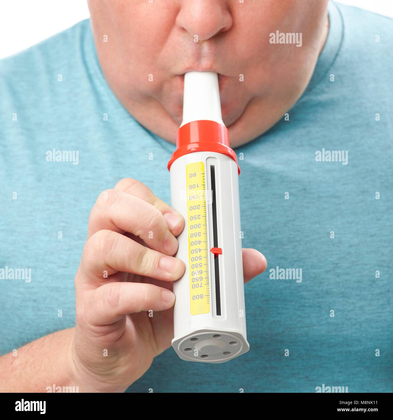 Overweight man using a peak flow metre. Stock Photo
