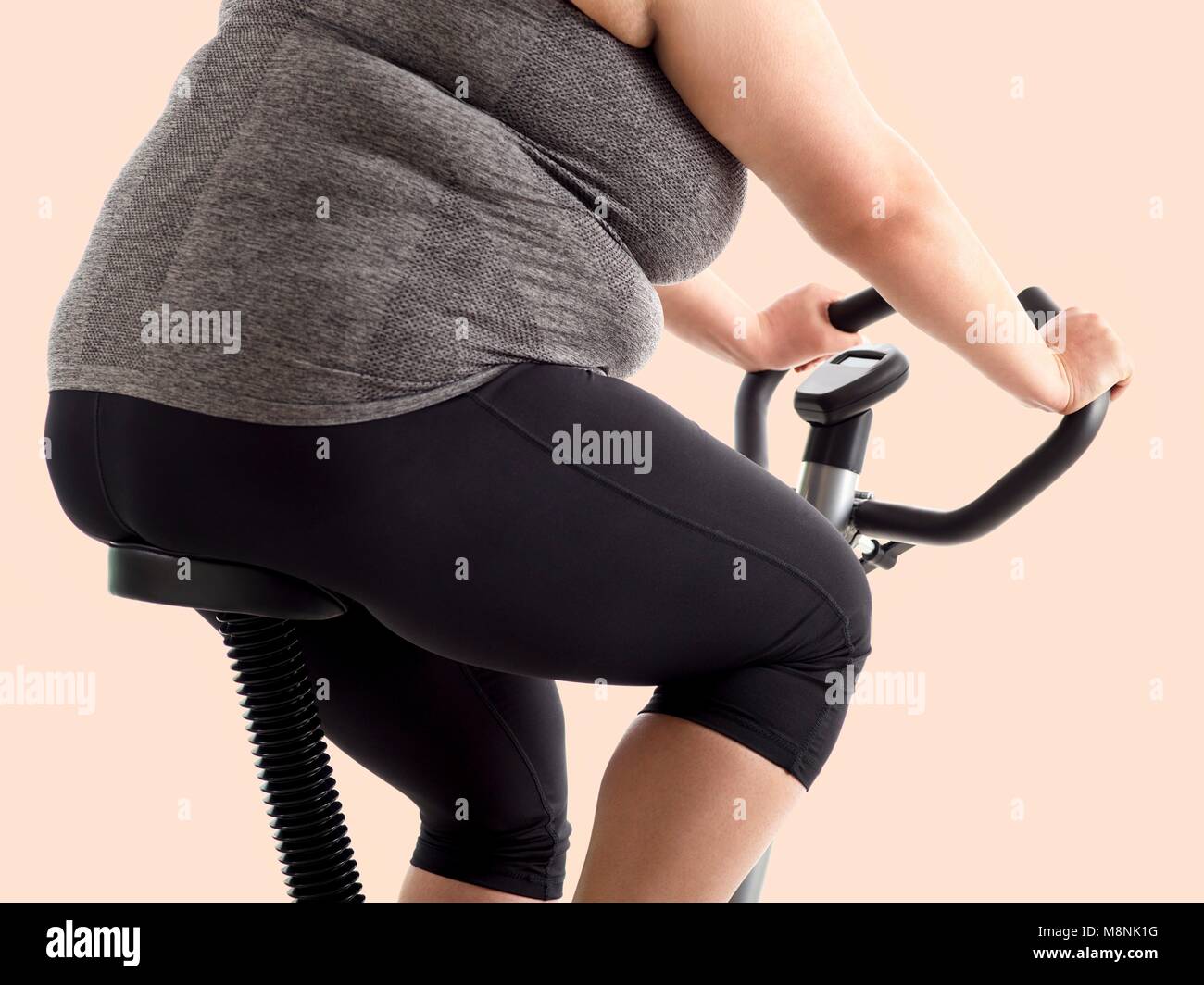 Overweight woman on exercise bike. Stock Photo