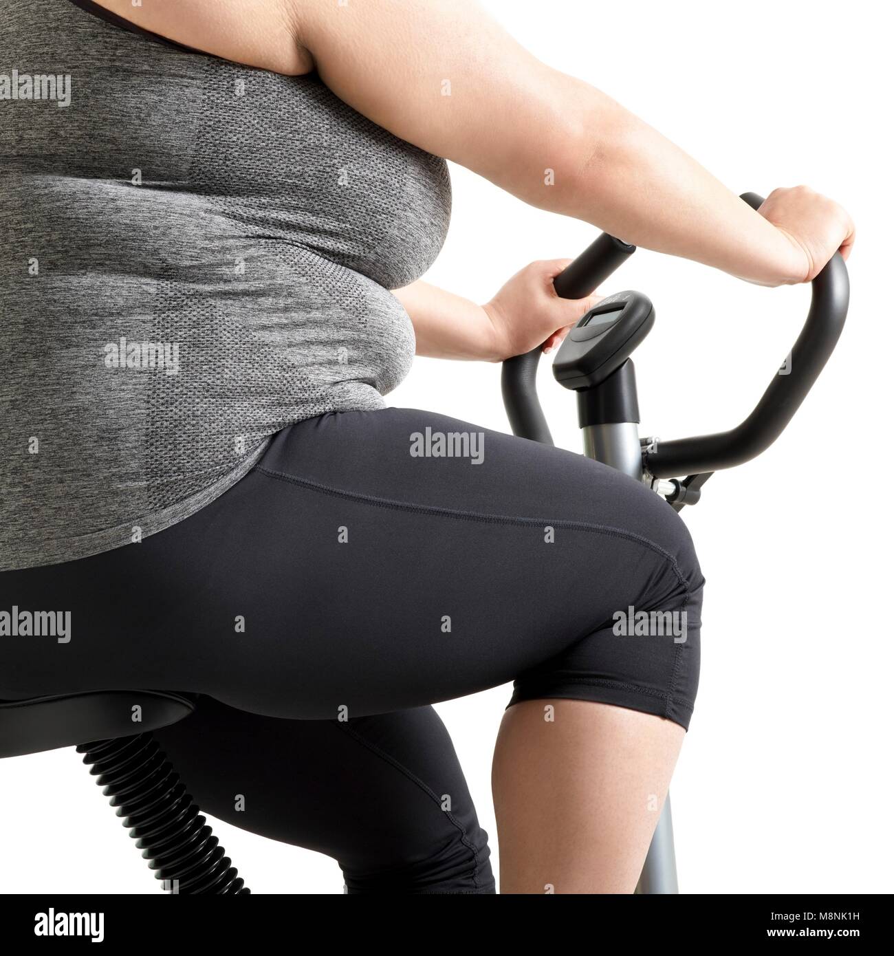 Overweight woman on exercise bike. Stock Photo