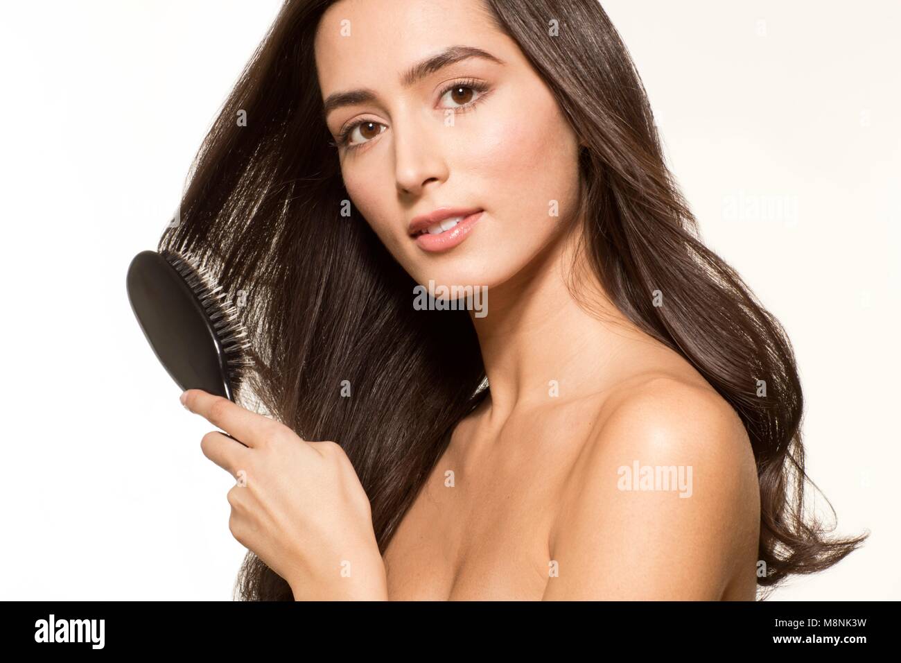 MODEL RELEASED. Young woman brushing long brown hair, portrait. Stock Photo
