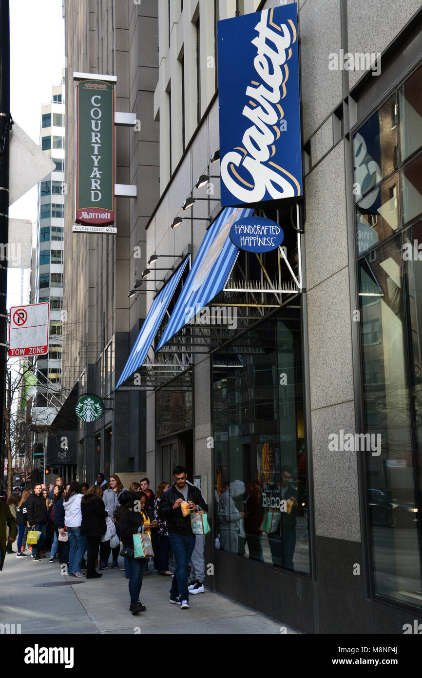 The line is out the door and down the sidewalk as people line up to buy gourmet popcorn from Garrett's Popcorn Shop off Chicago's Magnificent Mile. Stock Photo