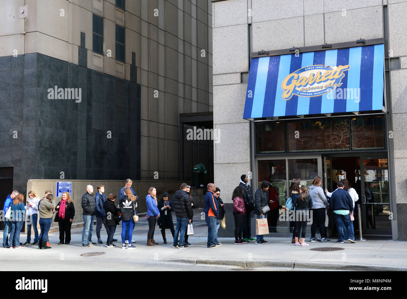 The line is out the door and down the sidewalk as people line up to buy gourmet popcorn from Garrett's Popcorn Shop off Chicago's Magnificent Mile. Stock Photo