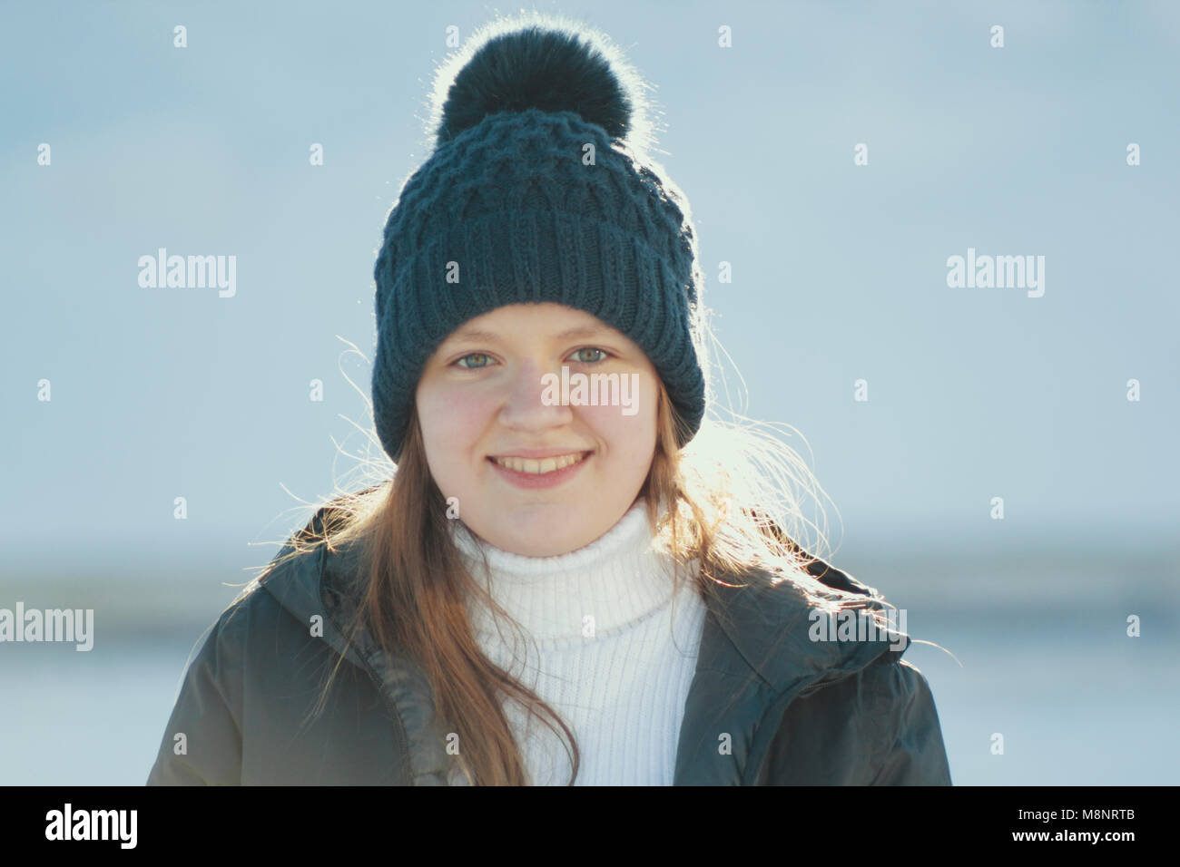 Portrait sunlit teenage girl wearing winter clothes in winter outside