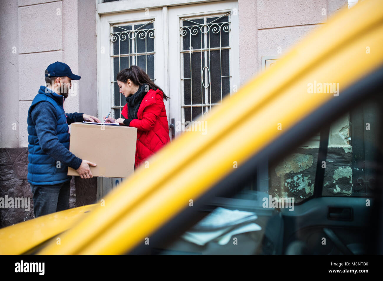 Woman receiving parcel from delivery man at the door. Stock Photo